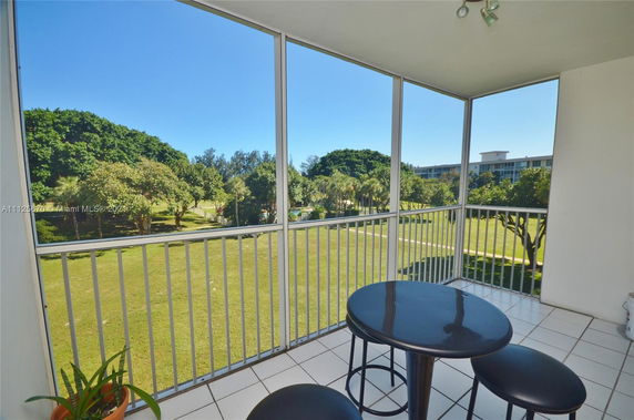 Balcony view overlooking a grassy area with trees and distant buildings.