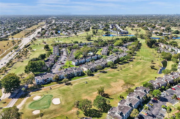 Aerial view of residential community with surrounding greenery and roads.