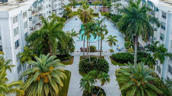 Exterior view of a residential building with a swimming pool and surrounding palm trees.