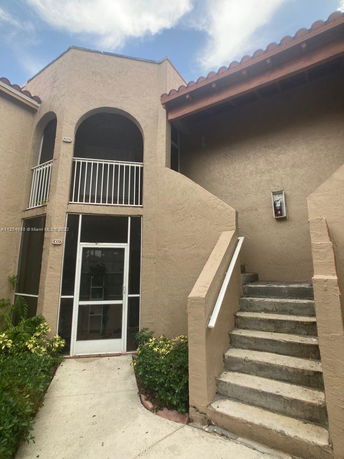 Front view of a two-story building with staircases and arches.