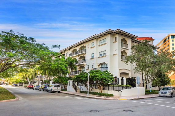 Front view of a multi-story residential building with balconies and a sloped roof.