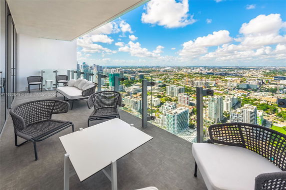 Outdoor seating area with a panoramic view of the city from a high-rise balcony.