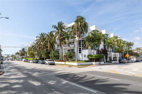 Front view of a modern multi-story building with palm trees.
