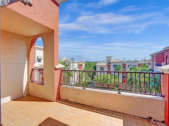Balcony view overlooking buildings and palm trees.