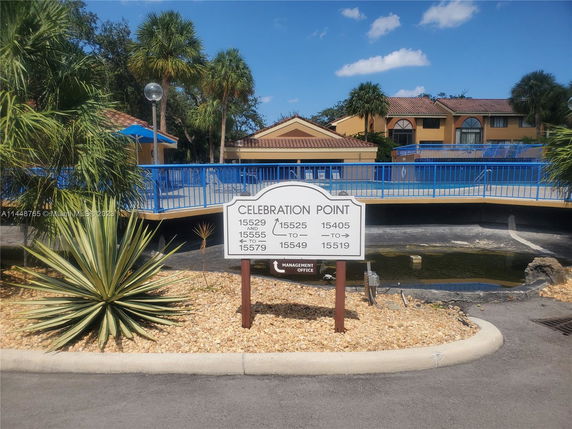 Front view of a building with blue railings and palm trees.