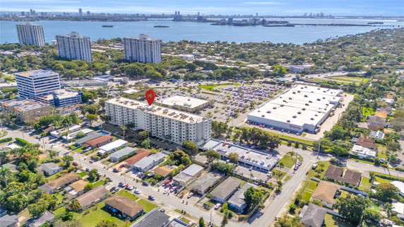 Aerial view of urban area with residential buildings, commercial properties, and a body of water in the distance.