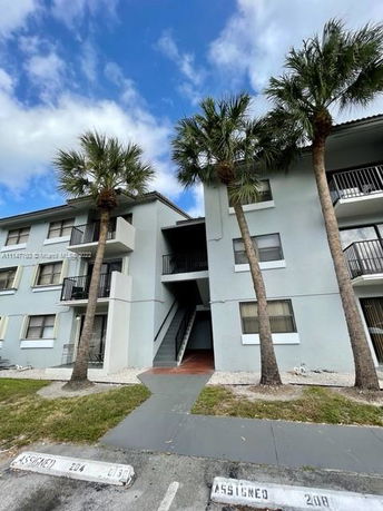 Front view of a multi-story residential building with balconies and palm trees.