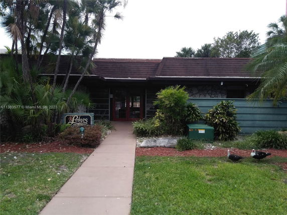 Front view of a one-story building with a sloped roof and a pathway leading to the entrance.
