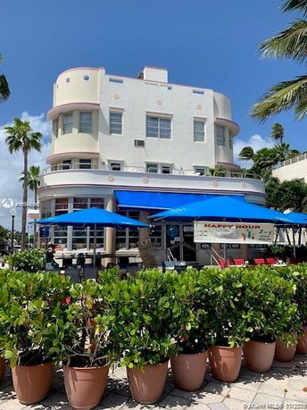 Front view of a multi-story building with curved architectural design and outdoor seating area.