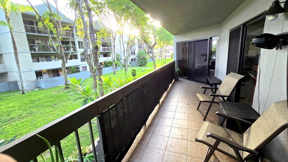 View from a balcony overlooking a grassy area and nearby apartment buildings.
