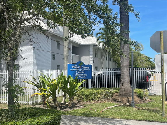 Front view of a multi-story condominium building with a fenced perimeter.