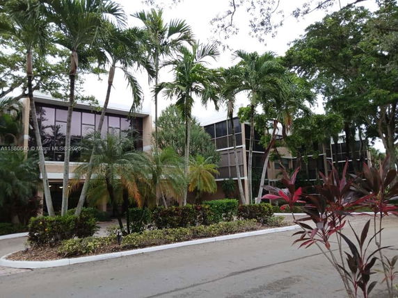 Front view of a multi-story building with large windows and palm trees.