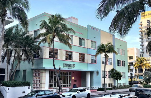 Front view of a pastel-colored multi-story building with palm trees.