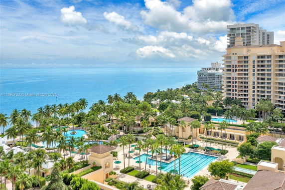 Panoramic view of a coastal area with resort buildings and swimming pools overlooking the ocean.