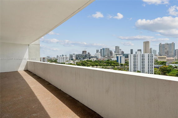 Panoramic view from a balcony overlooking a city skyline with multiple high-rise buildings.