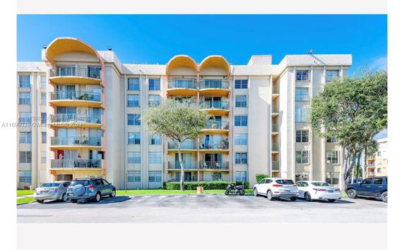 Front view of a multi-story apartment building with balconies and parking area.