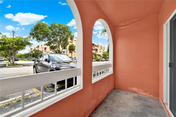 View from a small porch showing nearby buildings and parking area.