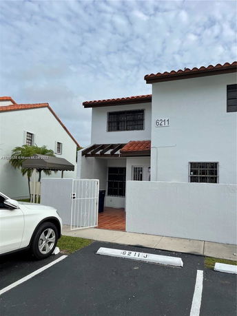 Front view of a two-story house with a gated entrance and parking area.