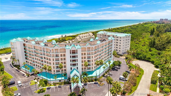 Elevated view of a multi-story building with turquoise roofs near the coastline.