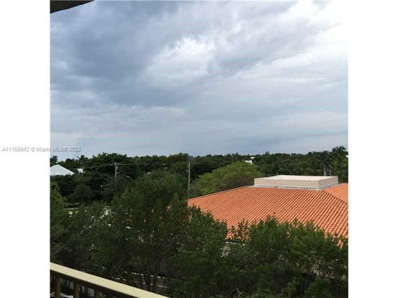 View of surrounding areas with trees and rooftops under a cloudy sky.