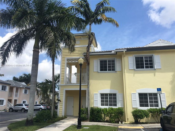 Front view of a two-story building with yellow exterior and white window shutters.