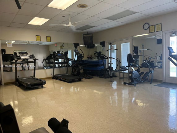 Indoor gym with treadmills, exercise bikes, and mirrors.