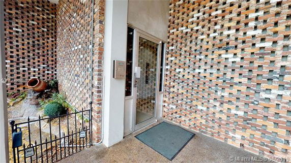 Entrance view of a building with patterned brick walls and a glass door.