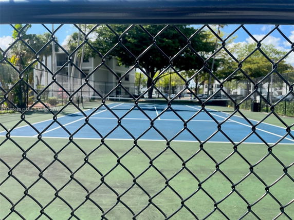 View of an outdoor tennis court surrounded by a fence.
