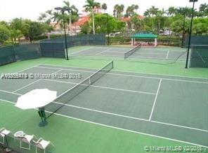 Tennis courts surrounded by greenery and palm trees.
