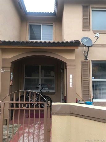 Front view of a two-story house with a gated entrance and satellite dish.