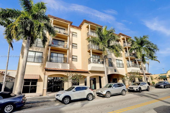 Front view of a multi-story building with balconies and palm trees.
