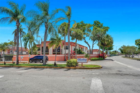 Front view of a two-story residential building with palm trees.