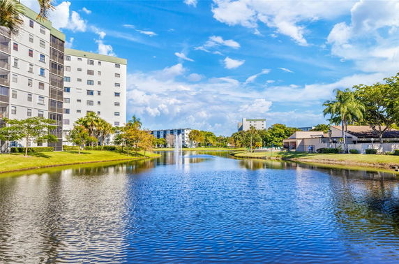 View of buildings along a water body with trees and a fountain.