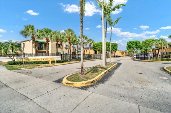 Front view of a residential building complex with palm trees.