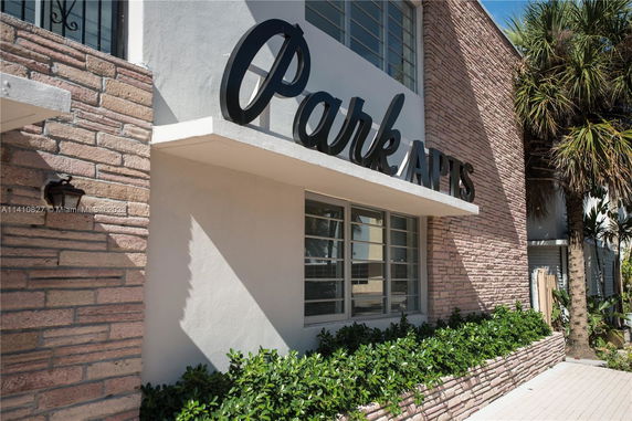 Front view of a building with brick and stucco facade, featuring a prominent sign.