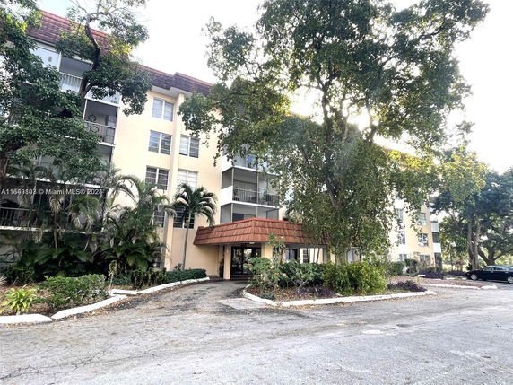 Front view of a multi-story residential building with balconies and an entrance canopy.