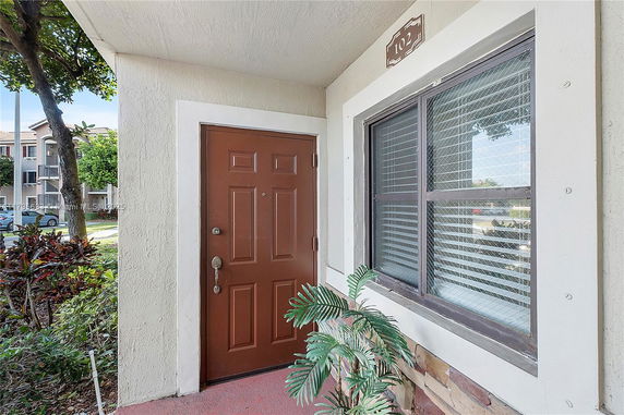 Entrance of a building unit with a brown door and adjacent window, marked as unit 102.