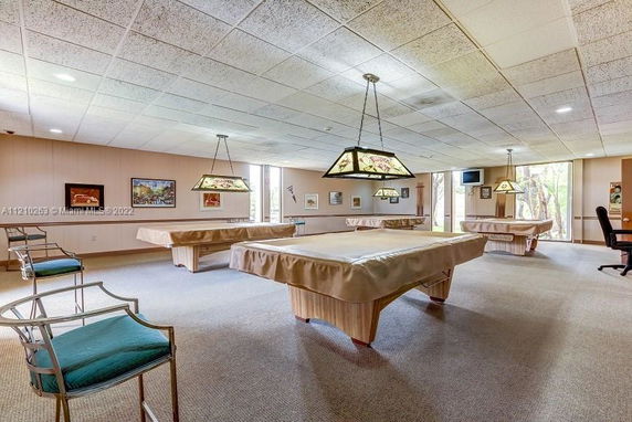 Interior of a recreation room with multiple pool tables and chairs.
