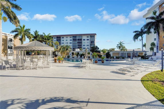 Outdoor area with swimming pool, seating, and shaded gazebo.