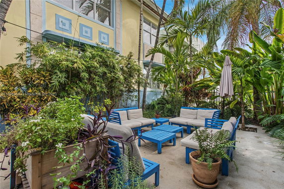 Outdoor seating area with blue furniture surrounded by lush greenery.