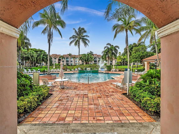 Outdoor swimming pool area with palm trees and a surrounding building.