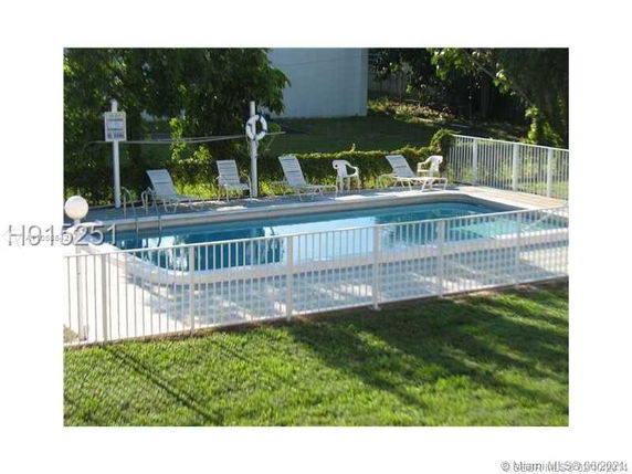 Outdoor swimming pool with a surrounding fence and lounge chairs.