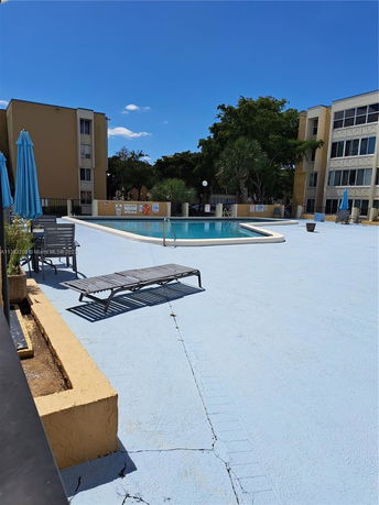Outdoor swimming pool area surrounded by buildings and trees.