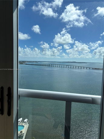 Panoramic view of a large body of water with a bridge crossing it, seen from a high-rise building window.