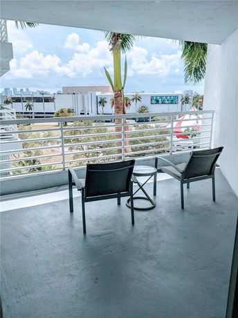 View of surrounding buildings and skyline from a balcony with chairs.