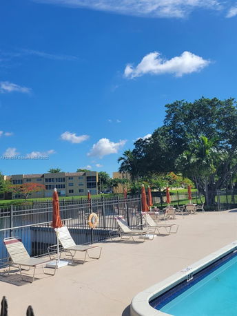 Outdoor swimming pool with lounge chairs and a fenced-off area.
