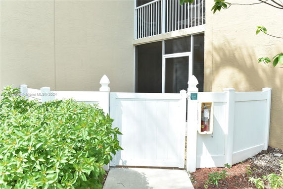 Front view of a building with a white picket fence and a screened balcony.