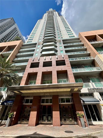 Front view of a tall modern building with multiple balconies and glass windows.
