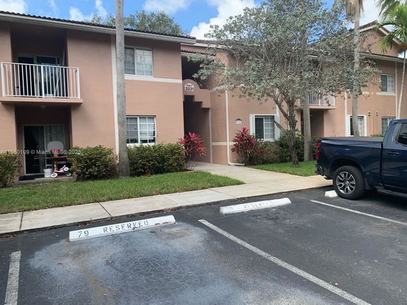 Parking area in front of a two-story building with balconies.