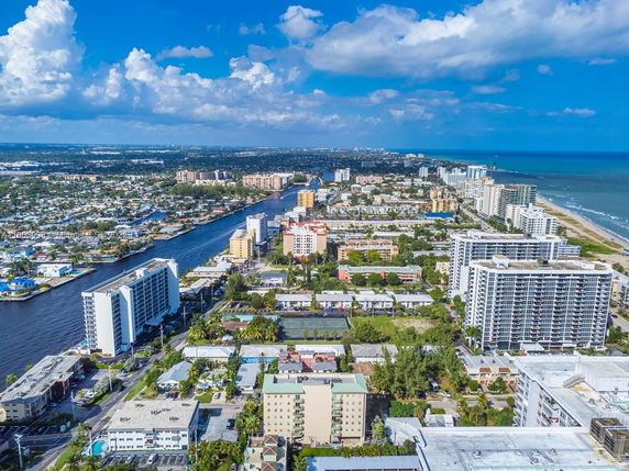 Aerial view of a coastal cityscape with high-rise buildings near a beach and a river.